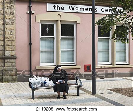 Stock Photo - United Kingdom, Northern Ireland, County Londonderry, Nun with her supermarket shopping outside Womans Centre; Derry. Fotosearch