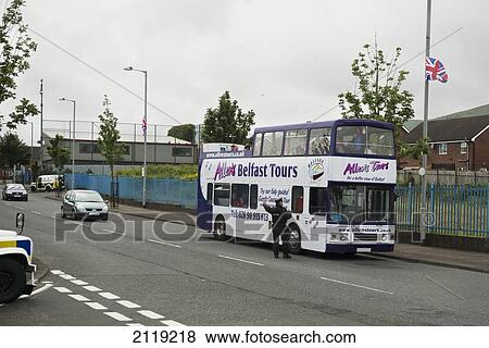 Stock Photo - United Kingdom, Northern Ireland, Policeman stopping double decker tour bus in loyalist sector of city; Belfast. Fotosearch