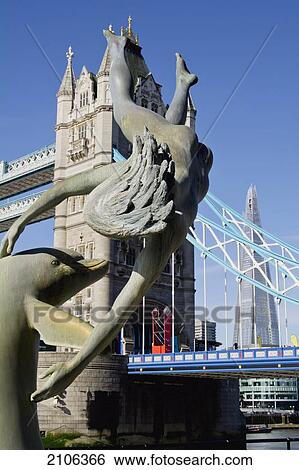 Stock Photograph - United Kingdom, Shard building in background; London, Girl with Dolphin statue in front of Tower Bridge. Fotosearch