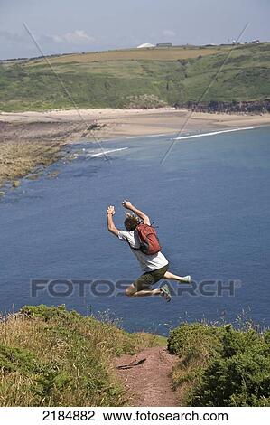 United Kingdom, Wales, Pembrokeshire, Hiker With Backpack Jumping On Coastal Path; Manorbier View Large Photo Image Stock Image - United Kingdom, Wales, Pembrokeshire, Hiker With Backpack Jumping On Coastal Path; Manorbier. Fotosearch