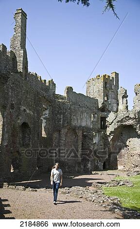 Stock Photograph - United Kingdom, Wales, Pembrokeshire, Man Walking By Laugharne Castle; Laugharne. Fotosearch
