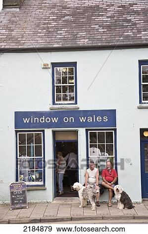 Stock Photo - United Kingdom, Wales, Two Men With Dogs Sitting In Front Of Shop; Pembrokeshire. Fotosearch