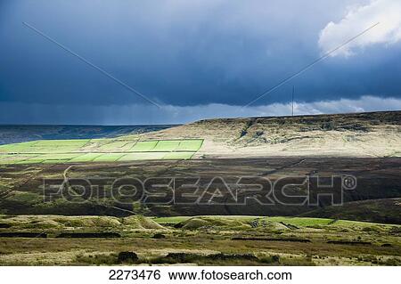 Stock Photograph - United Kingdom, West Yokrshire, Yorkshire Moors; Holmfirth and Digley Reservoir, and stormy weathers looms overhead, Farmed fields and rugged moorland sit side by side. Fotosearch