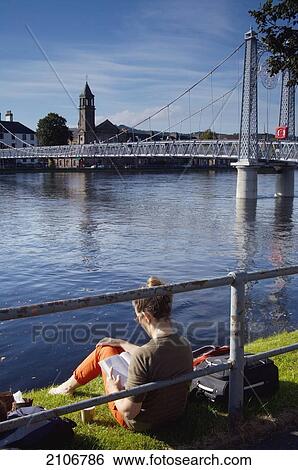 Stock Photograph - United Kingdom, Woman sitting next to river; Scotland. Fotosearch