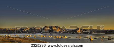 Stock Photograph - United States of America, Rocks in water and sunlight illuminating the shoreline at sunset on Powell River; Utah. Fotosearch