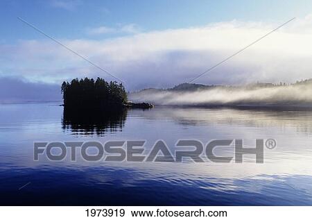 Stock Photo - USA, Alaska, Frederick Sound, Fog And Glassy Reflections On Water; Brothers Island. Fotosearch