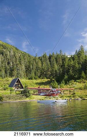 Stock Image - USA, Alaska, Prince William Sound, Shrode Lake, float plane parked by US Forest Service cabin.. Fotosearch