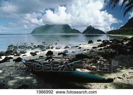 Stock Image - USA, American Samoa, Manu'a Island, Canoe docked near Smoldering Fire; Still Beach. Fotosearch