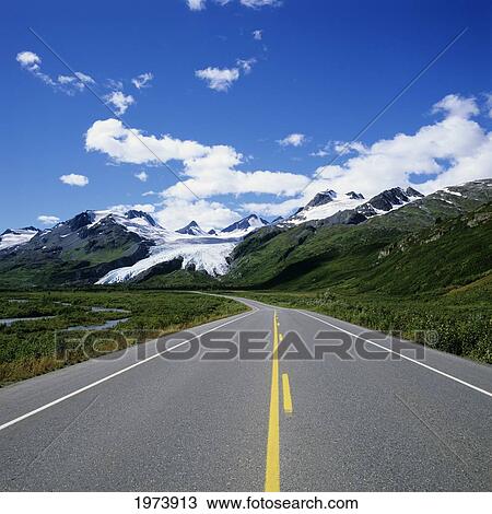Stock Image - USA, Blue Skies And Mountain Peaks In Distance; Alaska, Richardson Highway Leading To Worthington Glacier. Fotosearch