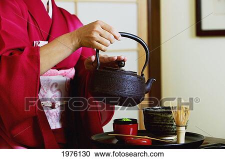 Stock Image - USA, California, Close Up Of Geisha Pouring Tea At Tea Ceremony; Santa Barbara. Fotosearch