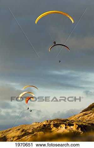 Stock Image - USA, California, Paragliders Flying Over Coast; La Jolla. Fotosearch