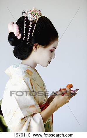 Stock Image - USA, California, Portrait Of Maiko Eating Sushi; Santa Barbara. Fotosearch