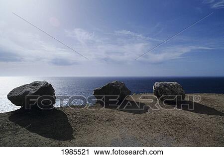 Stock Image - USA, California, Rocks on edge of cliff overlooking ocean's horizon; Big Sur. Fotosearch