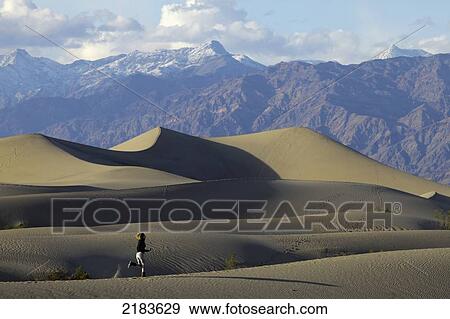 Usa, California, Young Woman Running On Mesquite Flat Sand Dunes With Amargosa Range Mountains In Background; Death Valley National Park View Large Photo Image Stock Photo - Usa, California, Young Woman Running On Mesquite Flat Sand Dunes With Amargosa Range Mountains In Background; Death Valley National Park. Fotosearch