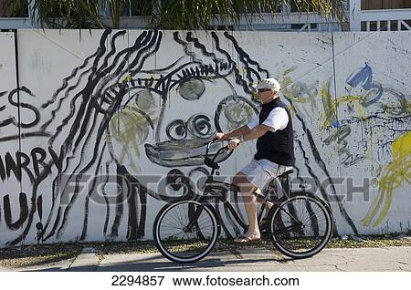 USA, Florida Keys, Male cyclist passes graffiti wall; Key West View Large Photo Image Stock Photo - USA, Florida Keys, Male cyclist passes graffiti wall; Key West. Fotosearch