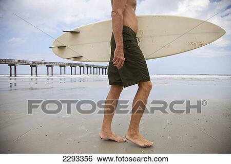Stock Photograph - Usa, Florida, Surfer Walking Towards Sea; St Augustine. Fotosearch