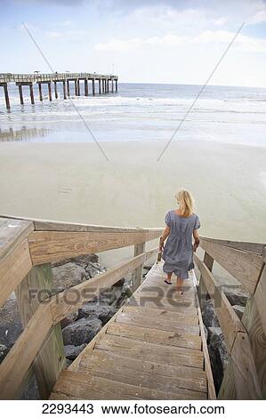 Stock Image - Usa, Florida, Woman On Wooden Steps Leading To Beach; St Augustine. Fotosearch