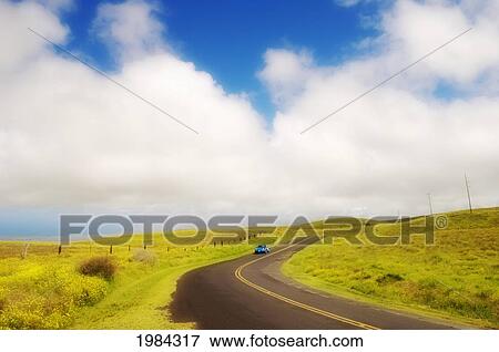 Stock Photo - USA, Hawaii Islands, Big Island, Car driving down Saddle Road curving through rolling grass hills near Waikii Ranch; South Kohala. Fotosearch
