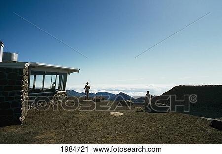 Stock Image - USA, Hawaii Islands, Haleakala Crater; Maui, People overlooking valley from lookout center. Fotosearch