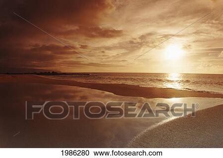 Stock Image - USA, Hawaii Islands, Oahu, Beach Tidepool next to ocean reflecting sunset sky; North Shore. Fotosearch