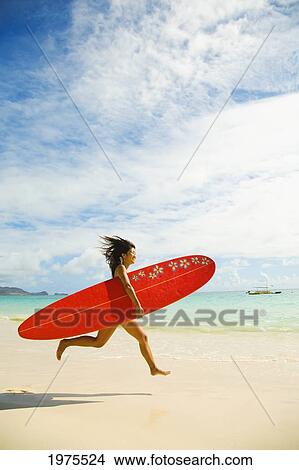 Picture - USA, Hawaii Islands, Oahu, Young Woman Running On Beach While Holding Red Surfboard; Lanikai. Fotosearch