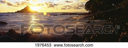 Stock Image - USA, Hawaii, Maui, View Of Sunrise Bursting Over Alau Island From Hana Shoreline; Hana. Fotosearch