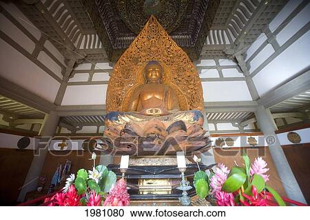 Stock Image - USA, Hawaii, Oahu, Buddha statue surrounded by flowers in Byodo-In Temple in Valley Of Temples Memorial Park; Ahuimanu Valley. Fotosearch