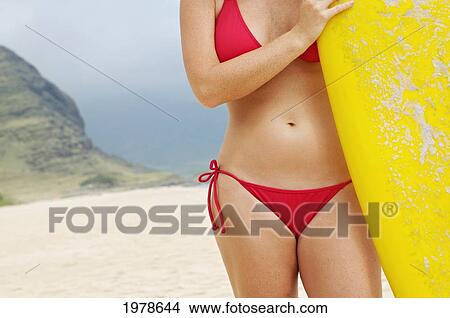 Picture - USA, Hawaii, Oahu, Mid section of woman on beach with yellow surfboard; Honolulu. Fotosearch