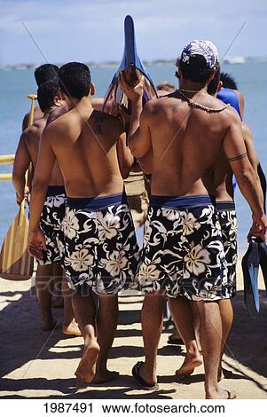 Stock Image - USA, Hawaii, Oahu, Paddlers carrying boat to water; Keehi Lagoon. Fotosearch