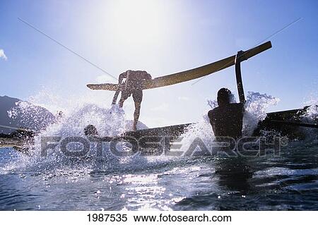 Stock Photography - USA, Hawaii, Oahu, Paddlers turning over outrigger canoe that has flipped; Makaha. Fotosearch