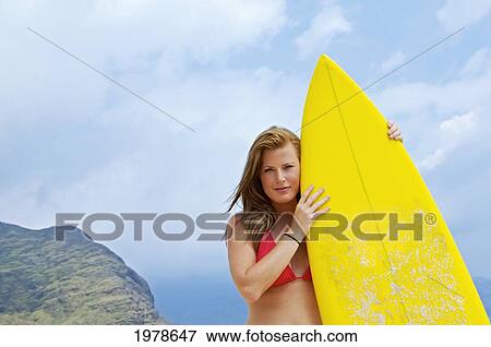 Stock Photo - USA, Hawaii, Oahu, Portrait of woman on beach with yellow surfboard; Honolulu. Fotosearch