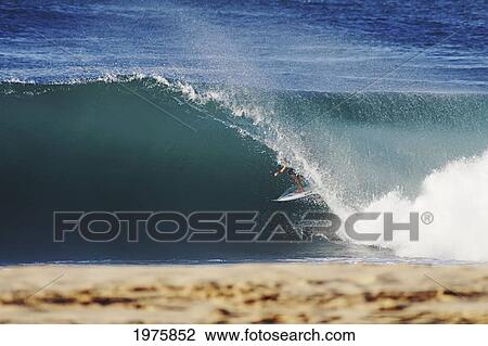 Stock Image - USA, Hawaii, Oahu, Surfer Riding Wave; North Shore, Pipeline. Fotosearch