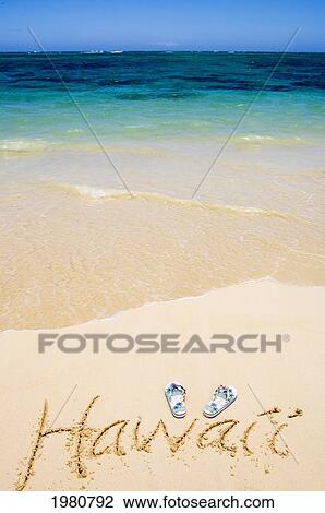 Stock Image - USA, Hawaii, Ocean in background; Kailua, Flipflops and Hawaii written in sand. Fotosearch