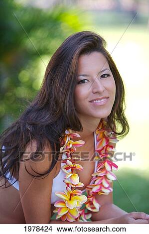 Picture - USA, Hawaii, Portrait of woman with yellow Plumeria behind ear and Plumeria Lei Around Her Neck; Oahu. Fotosearch