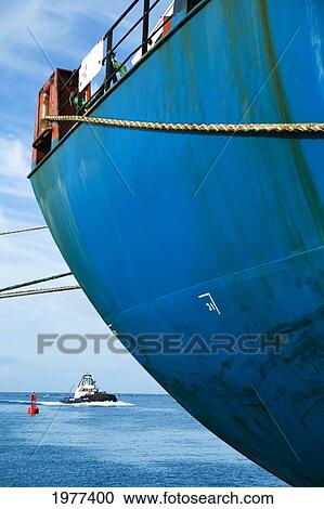 Stock Image - USA, Hawaii, View of tugboat and docked ship in harbor; Honolulu. Fotosearch