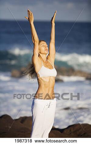 Stock Photo - USA, Hawaii, Young woman doing yoga near Pacific Ocean; Maui. Fotosearch