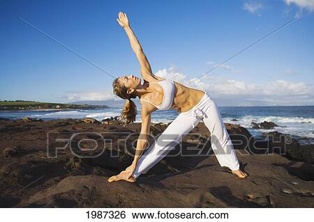 Stock Photograph - USA, Hawaii, Young woman doing yoga near Pacific Ocean; Maui. Fotosearch