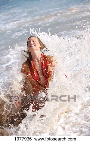 Stock Photograph - USA, Hawaii, Young woman getting splashed by wave; Oahu. Fotosearch