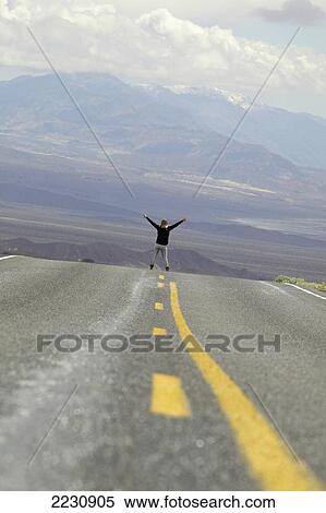 Stock Photography - Usa, Nevada, Young Woman Standing On Deserted Route 374 In Death Valley National Park; California. Fotosearch