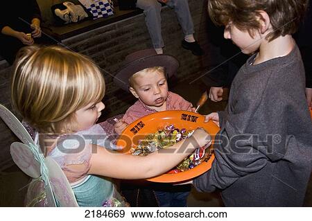 Usa, New York State, Children In Halloween Costumes Examining Bowl Of Sweets; New York City View Large Photo Image Stock Photo - Usa, New York State, Children In Halloween Costumes Examining Bowl Of Sweets; New York City. Fotosearch