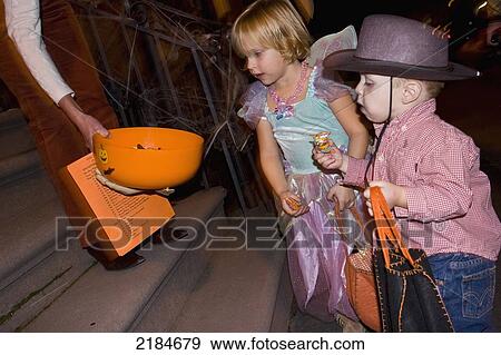 Stock Photo - Usa, New York State, Children In Halloween Costumes Receiving Sweets; New York City. Fotosearch