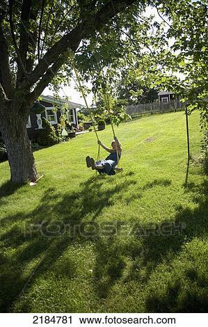Stock Image - Usa, New York State, Girl Swinging In Garden; Hudson Valley. Fotosearch