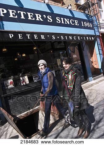 Stock Image - Usa, New York State, New York City, Brooklyn, Williamsburg, Two Women Passing By Shop; Bedfort Street. Fotosearch