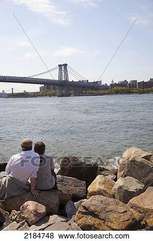 Stock Photo - Usa, New York State, New York City, Views Of Williamsburg Bridge And Manhattan; Brooklyn, Couple Sitting At Grand Street Park. Fotosearch