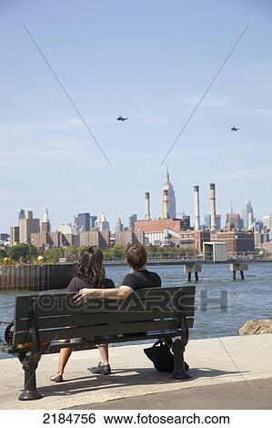 Stock Photograph - Usa, New York State, New York City, Couple Sitting At Grand Street Park Looking At Manhattan; Brooklyn. Fotosearch