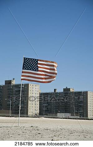 Stock Photography - Usa, New York State, Us Flag In Sand With Estate Housing In Background; Rockaway. Fotosearch