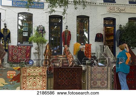 Stock Photograph - USA, Shoppers outside fabric and rug store at Eastern Market. DC's Oldest Continually Operated Fresh Food Public Market; Washington DC. Fotosearch