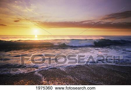 Stock Image - USA, Sunset Illuminates Ocean; Hawaii Islands, Beautiful Wave Crashing On Shoreline. Fotosearch