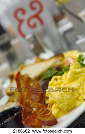 Stock Image - USA, Traditional American breakfast at Kramer books and afterwards. This is a local instition offering a wide selection of books a bar and live music; Washington DC, Plate of scrambled eggs and bacon. Fotosearch