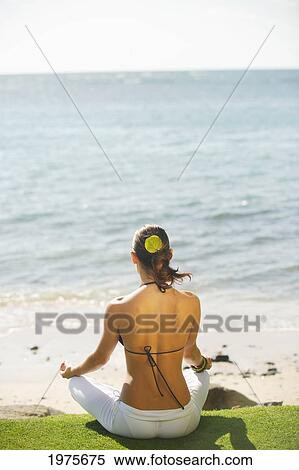 Stock Photography - USA, View From Behind; Hawaii Islands, Woman Meditating On Grass Near Ocean. Fotosearch
